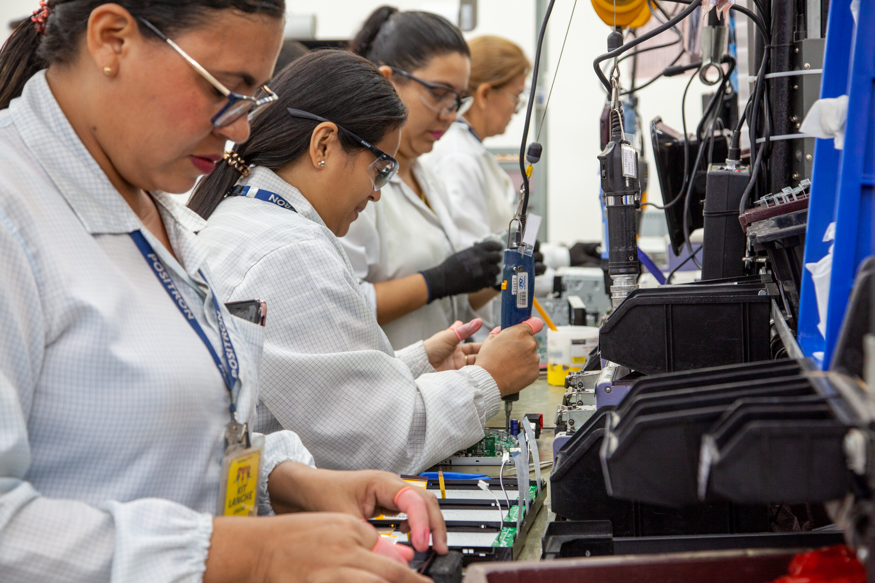 Side profile view of women working in a warehouse setting in white lab coats
